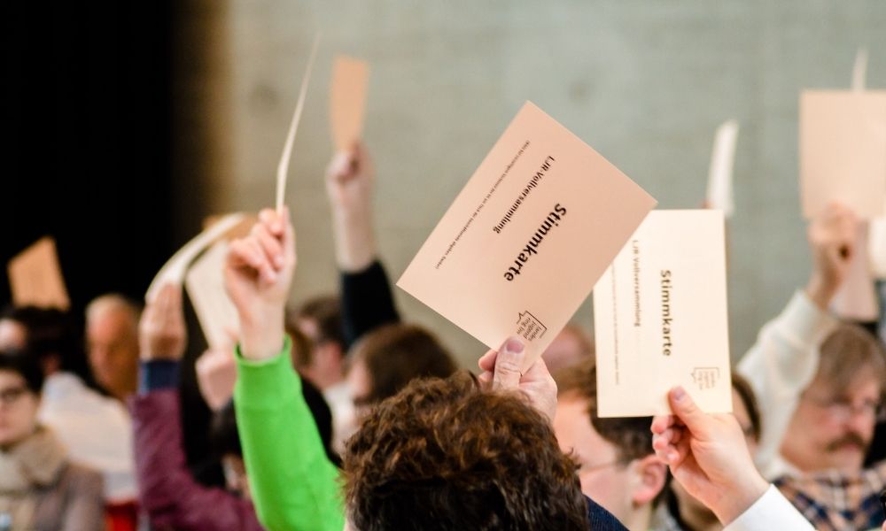 viele junge Menschen bei einer Versammlung halten Stimmkarten in die Luft