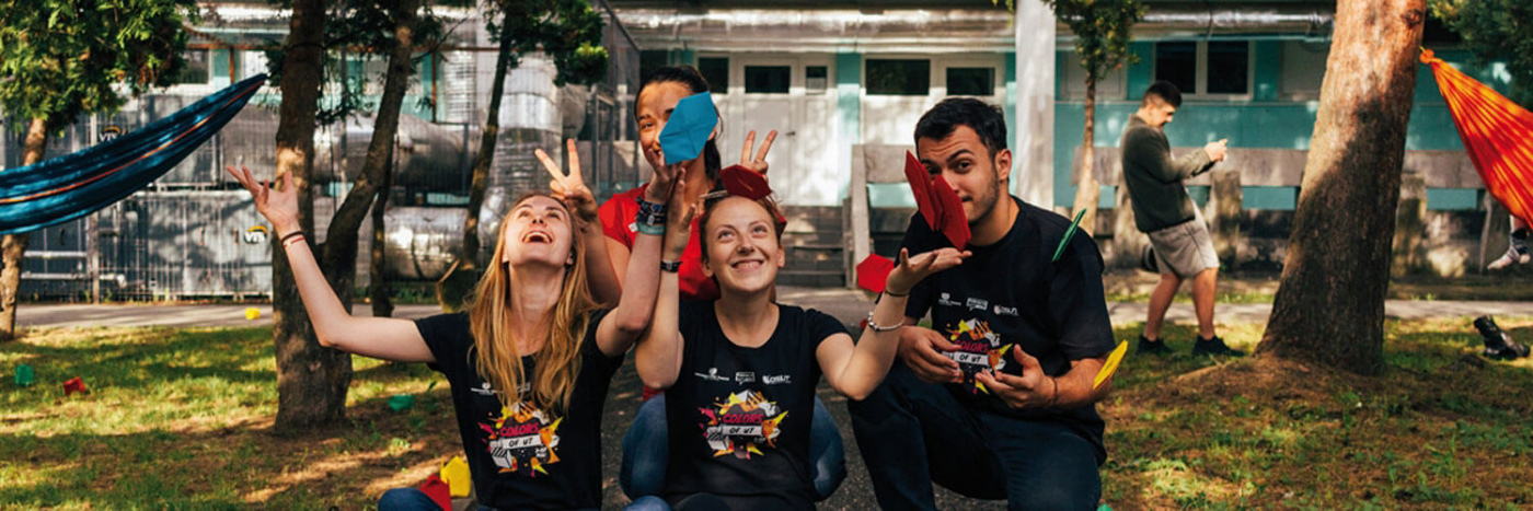 eine Gruppe junger Menschen wirft in einem Garten Konfetti in die Luft