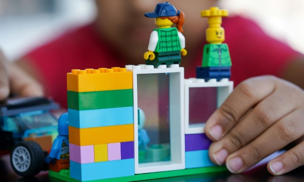 ein Kind baut ein Haus aus bunten Klemmbausteinen.